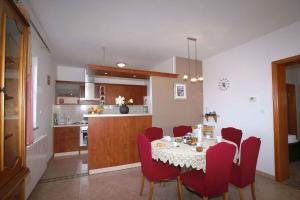 a dining room and kitchen with a table and red chairs at Apartment in Malinska/Insel Krk 12860 in Vantačići