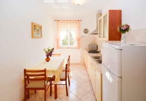a kitchen with a table and chairs and a white refrigerator at Apartment Vinkuran 6 in Vinkuran
