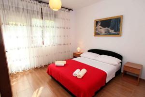 a bedroom with a red bed with two towels on it at Apartment Okrug Donji 6 in Okrug Gornji