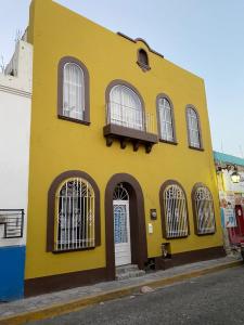 a yellow building with windows and a white door at My Family In Monterrey - Hostel in Monterrey
