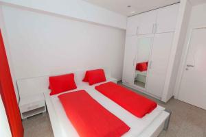 a white bedroom with red pillows on a bed at Apartment Crikvenica 20 in Crikvenica