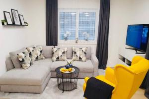 ein Wohnzimmer mit einem Sofa, einem Tisch und gelben Stühlen in der Unterkunft LEON Apartment NEU! Gemütlichkeit an erster Stelle in Linz