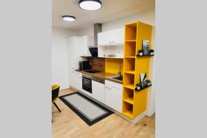 kuchnia z białymi szafkami i żółtą półką w obiekcie LEON Apartment NEU! Gemütlichkeit an erster Stelle w Linzu