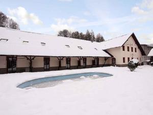 a building covered in snow with a pool in the yard at Apartments in Desna - Isergebirge 1786 in Šumburk nad Desnou