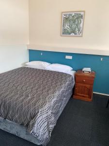 a bedroom with a bed and a wooden nightstand with a bed sidx sidx sidx at Allambie Motel in Condobolin