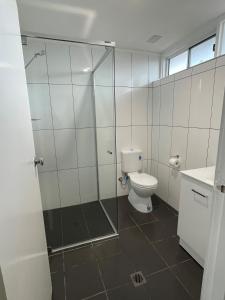 a bathroom with a toilet and a glass shower at Allambie Motel in Condobolin