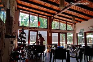 a woman standing at a table in a restaurant with a christmas tree at Complejo Casa Caracolnegro in Mar de Cobo