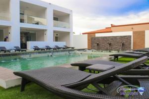 a swimming pool with tables and chairs in front of a building at Departamento Turquesa 3 joyas de mar San Carlos in San Carlos