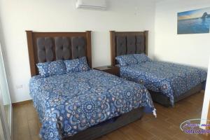 a bedroom with two beds with blue comforters at Departamento Turquesa 3 joyas de mar San Carlos in San Carlos +32 photos