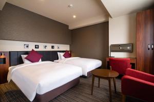 a hotel room with two beds and a red chair at Goi Grand Hotel in Ichihara