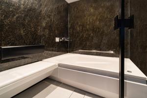 a bathroom with a white tub and a black wall at Goi Grand Hotel in Ichihara