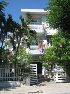 a white building with palm trees in front of it at The Moon Villa Hoi An in Hoi An