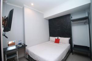Schlafzimmer mit einem weißen Bett und einem schwarzen Kopfteil in der Unterkunft Bale Resident in Jakarta