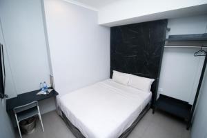 ein kleines Schlafzimmer mit einem weißen Bett und einer schwarzen Wand in der Unterkunft Bale Resident in Jakarta