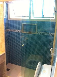 y baño con ducha de azulejos verdes y aseo. en Best Barra Beach Apartment, en Río de Janeiro