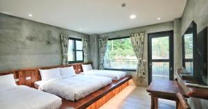 um quarto com 2 camas, uma secretária e janelas em 里夏民宿.墾丁後壁湖 em Hengchun South Gate