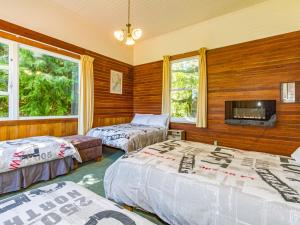 two beds in a room with wooden walls and windows at The Station - Ohakune Holiday Home in Ohakune