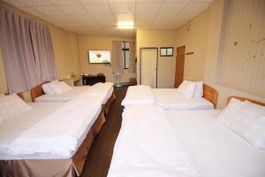 um quarto de hospital com quatro camas seguidas em Zhongshan Hostel em Fenqihu