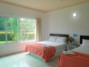 a bedroom with two beds and a window at Hotel Parotas Manzanillo in Manzanillo