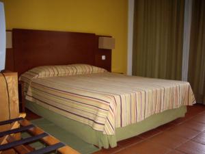 a bedroom with a large bed with a wooden headboard at Bamboo Xaguate Hotel in São Filipe