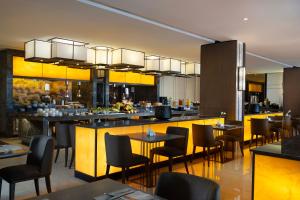 a restaurant with a bar with tables and chairs at GRAMM HOTEL by Ambarrukmo Yogyakarta in Yogyakarta