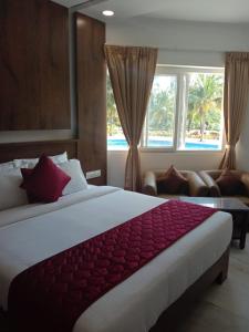 a bedroom with a large bed and a large window at coral beach resort in Mahabalipuram