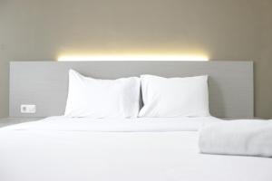 a large white bed with white pillows at Stylish Studio Apartment at Harvard Jatinangor near ITB By Travelio in Sayang +5 photos
