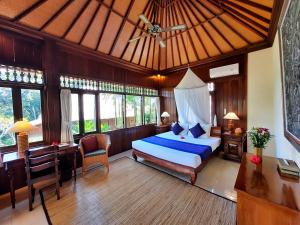 a bedroom with a bed and a desk and windows at Alam Indah Ubud in Ubud