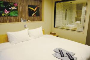 a bedroom with a white bed with a mirror and a sink at Shiki Suites - Kyoto Umekoji in Kyoto