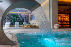 ein Pool mit einem Springbrunnen vor einem Gebäude in der Unterkunft Hotel Belmont & Spa in Sinaia