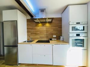Violet Apartment by Alex Rafael في زغرب: مطبخ مع دواليب بيضاء وثلاجة ستانلس ستيل