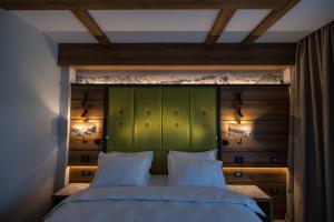una camera da letto con testiera verde e 2 cuscini bianchi di Hotel Belmont a Sinaia