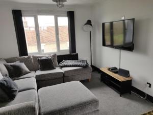 a living room with a couch and a flat screen tv at Riverside Park Penthouse Apartment In St Neots in Saint Neots