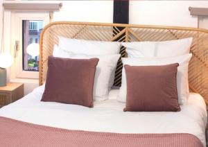 Una cama con almohadas blancas y marrones. en Duplex - Le Cosy - Hyper Centre, en Haguenau