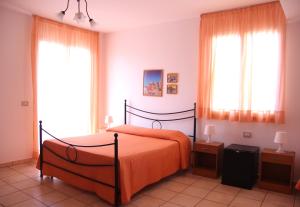 a bedroom with a bed with orange sheets and windows at Fragolina B&B in Furci Siculo