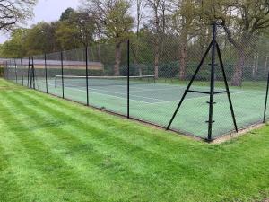 a fence with two tennis courts on a grass field at Whitmoor Farm & Spa in Guildford