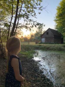 Una niña caminando por un arroyo delante de un granero. en AMANI - Aap, en Lichtaart