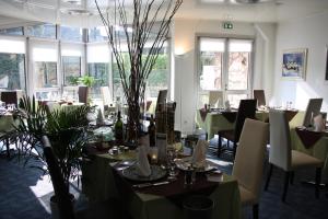 a dining room with tables and chairs and windows at La Berteliere, The Originals Relais in Saint-Martin-du-Vivier