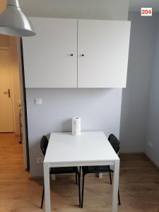 a white table with two chairs and a white cabinet at Immoappart in Albi