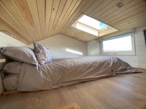 a bed in the middle of a room with a window at The Cedar Tiny House in Coldingham