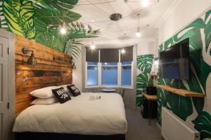 Un dormitorio con una cama blanca con hojas verdes en la pared en Blok-74 en Brighton & Hove