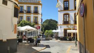 una calle de la ciudad con mesas, sillas y edificios en Misterhost Santa Cruz II -Jardines de Murillo, en Sevilla