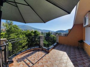 a balcony with an umbrella and mountains in the background at Apartman Nidžo in Trebinje +1 photo
