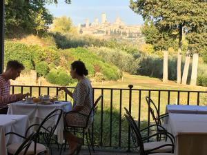 a man and woman sitting at a table with a view at Tenuta Guardastelle - Agriturismo and vineyard in San Gimignano