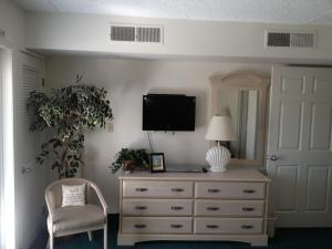 um quarto com uma cómoda, uma televisão e uma cadeira em Biscayne Suites em Ocean City