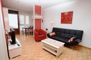 a living room with a black couch and a red chair at La Caseta - 5907 in Isla