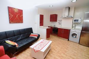 a living room with a black couch and a kitchen at La Caseta - 5907 in Isla