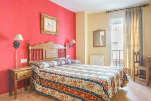 1 dormitorio con cama y pared roja en Arunda I, en Ronda