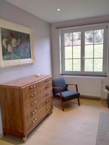 a living room with a dresser and a chair and window at L'Aubergine in Sprimont