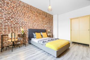 Un dormitorio con una pared de ladrillo y una cama. en UNO Apartaments, en Katowice